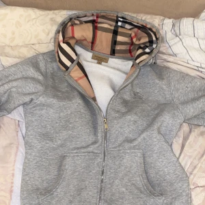 Burberry hoodie - Säljer grå hoodie från Burberry med dragkedja. Riktigt bra skick. Knappt använd. Ej nopprig, ej förstört material utan precis som en helt ny. 