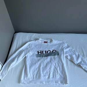 Vit sweatshirt från Hugo Boss - Säljer en stilren vit sweatshirt från Hugo Boss. Den är i storlek M men är lite kort så tror den passar bättre om du har S eller XS. Ställ gärna frågor om du undrar över något.