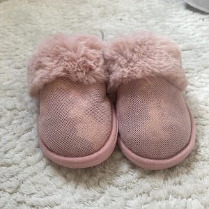Rosa tofflor med fluffig päls - Mysiga rosa tofflor med fluffig päls runt kanten. Perfekta för att hålla fötterna varma och bekväma. Sulan har ett mönster för extra grepp. Storlek 36/37.    +frakt 