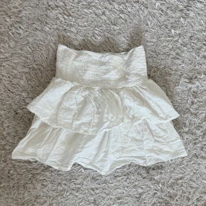 Vit volangkjol - Söt vit kjol med volanger och broderade detaljer. Den har en elastisk midja för bekväm passform. 