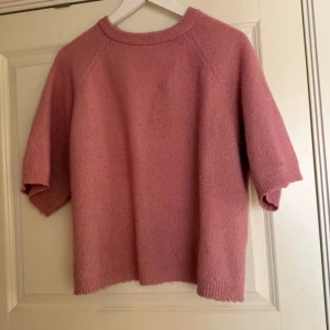 Rosa cashmere tröja odd Molly  - Säljer en mysig rosa stickad tröja med korta ärmar. Perfekt för lager på lager-stil under kyligare dagar. Tröjan har en enkel design med ribbade kanter vid hals och ärmslut.