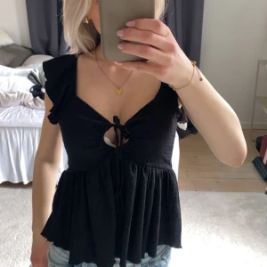 Svart topp med volangärmar - Säljer en svart topp med volangärmar och knytning framtill💕Aldrig använd💖