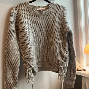 Grå stickad tröja med snörning - Säljer en snygg grå stickad tröja men snörning . Väldigt unik 
