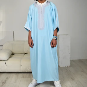 Ljusblå/silver marockansk thobe - Snygg ljusblå kaftan med detaljerat broderi runt halsen. Den har en lös passform och korta ärmar, perfekt för en avslappnad stil. Passar bra till sneakers för en modern look. En väldigt fin och unik marockansk thobe säljer den pga den var för stor för mig och returen kostar ungefär lika mycket som summan jag betalade den är stor i storleken säljer för ungefär samma pris jag köpte den för inklusive frakt och tull kostnaderna 