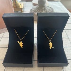 Arrow heart halsband  - Två matchande guld  halsband med delade hjärthängen – perfekta att dela med en vän eller partner. Halsbanden är 100 % rost- och nickelfria. Kedjorna är 40 cm långa men kan förlängas med ytterligare 5 cm. Hör gärna av dig om du har några frågor ☺️