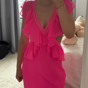 Lång volangklänning  - Supersnygg rosa lång klänning från Asos. Använd 1 gång, tyvärr blev det ett litet hål i klänningen då dragkedjan fastade i tygen( se sista bild) 🩷klänningen går ner till marken på mig. Jag är runt 165.