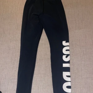 Svarta Nike leggings - Svarta leggings från Nike i storlek XS med stort vitt 'JUST DO IT.'-tryck längs ena benet. Tight passform och elastisk midja. Perfekta för träning eller chill. Materialet är mjukt och stretchigt för maximal komfort. Texten är inte helt vitt som ni ser på bilden. Bild även befogad på tråden som har lossnat:)