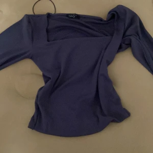 Mörkblå långärmad topp från Amisu - Säljer en lila långärmad topp från Amisu med snygg asymmetrisk halsringning. Toppen är figurnära och har en stilren, enkel design som passar perfekt till jeans eller kjol. Materialet är mjukt och stretchigt för en bekväm känsla.
