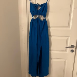 Blå långklänning från Zara  - Supersnygg blå somrig långklänning från Zara i linne. Klänningen har smala axelband, cut-outs i midjan, slits framtill och öppen rygg med korsknytning. Den är helt oanvänd med prislapp på, den är i storlek M och kostade ca 350kr ny men säljer den för 150kr