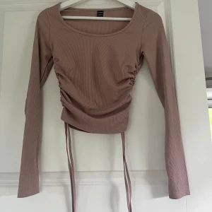 Beige ribbad topp med snörning - Trendig beige långärmad topp från Shein med ribbad struktur och snygg snörning i sidorna som ger en croppad look. Rund halsringning och smal passform gör den perfekt till jeans eller kjol.