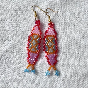 Färgglada pärlörhängen i fiskform - Unika örhängen i form av fiskar, handgjorda av mig med metoden ”brickbeading” av små pärlor i rosa, rött, orange, blått och vitt. Perfekt till sommaren!