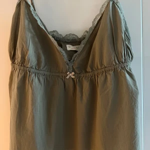 Khakigrön/ olivgrön linnetopp Odd Molly spets- stl 4 (XL) - Supersöt khakigrön linnetopp från Odd Molly med tunna axelband, spetskant längs ringningen och liten rosett framtill. Broderad Odd Molly-logga på ryggen och dekorativ etikett nertill. Perfekt för en chill och snygg look. Och den är i fint skick 