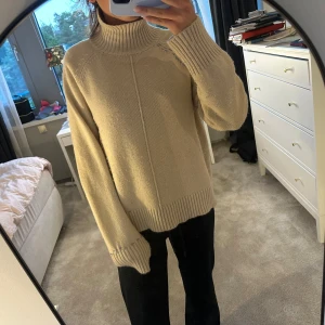 Beige stickad polotröja med raglanärm - Säljer en skit snygg beige stickad polotröja med hög ribbad krage och raglanärmar. Snygg detaljsöm framtill och längs axlarna. Tröjan sitter mer oversized🥰