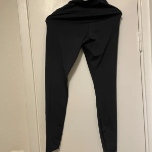 Svarta leggings från Iconic, stl S - Svarta leggings från Iconic i storlek S. De är tighta och har hög midja, perfekta för träning eller chill. Gjorda i ett stretchigt syntetmaterial som sitter skönt mot kroppen.