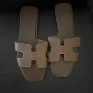 Bruna sandaler med fyrkantig tå - Snygga bruna sandaler med breda remmar i skinn och fyrkantig tå. Remmarna har ett stilrent, grafiskt utskuret mönster och sandalerna har platt sula. Perfekta för varma dagar och enkel att matcha med olika outfits.