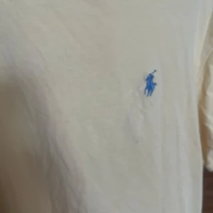 Gul t-shirt från Ralph Lauren - Gul t-shirt från Ralph Lauren med klassisk blå logga broderad på bröstet. T-shirten har rund halsringning och korta ärmar. Tillverkad i mjuk bomull för en skön känsla och avslappnad passform.