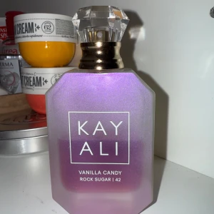 Kayali Vanilla Candy Rock Sugar 42 - Kayali Vanilla Candy Rock Sugar 42 i 50ml är en parfym i en snygg lila-rosa skimrande flaska med kristalliknande kork och guldiga detaljer. Doften är söt och gourmand med tydliga inslag av vanilj och sockrig karamell. Perfekt för dig som älskar söta och lekfulla dofter. Halva flaskan kvar!