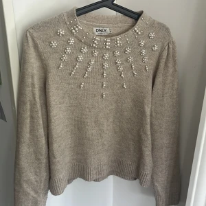 Beige stickad tröja med pärlor från ONLY - Superfin beige stickad tröja från ONLY med pärldetaljer över bröstet och runt halsen. Jag älskar verkligen den här tröjan men den har inte kommit till så mycket användning. Den är i storlek M men jag skulle säga att den är mellan M och S. 