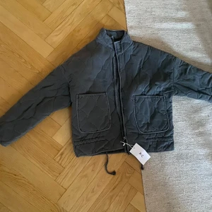 Quiltad grå jacka, Zara, grå  - Quiltad grå jacka från XC i boxig modell med stora fickor framtill och dragsko i nederkant. Jackan har hög krage, lång ärm och stängs med dragkedja. Perfekt för lager-på-lager och chill stil. Liknar en eftertraktad jacka som sålts på Zara men som nu är slutsåld. Jackan är aldrig använd. Storlek s, oversize (bredden) men skulle säga att den är något kort i ärmen. Så passar en xs eller en mindre s pga detta. Hämtas på Gärdet eller skickas mot en fraktkostnad.