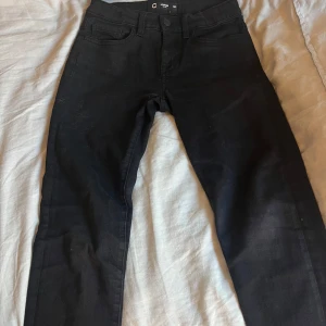 Svarta slim jeans från Cubus - Svarta jeans från Cubus med slim fit. Byxorna har mellan midja och är tillverkade i stretchigt bomullsmaterial för en bekväm passform. Perfekta för dig som gillar en stilren och enkel look.