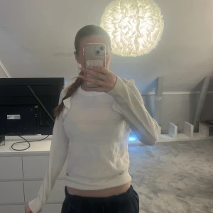 Vit stickad tröja med volang från Marine - Supersöt vit stickad tröja från Marine i storlek S. Tröjan har långa ärmar och snygga volangdetaljer på axlarna som ger en extra touch. Perfekt för dig som gillar en feminin och stilren look. Mjuk och skön att bära.