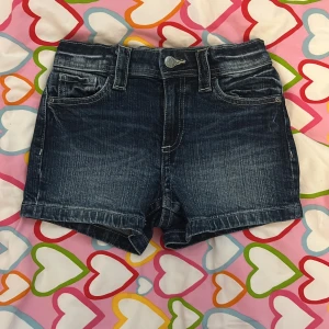 Mörkblå jeansshorts från H&M - Snygga mörkblå jeansshorts från H&M med klassisk femficksdesign och coola slitningar. Shortsen har bälteshällor, knapp och dragkedja framtill samt bakfickor med lock och knapp. Perfekta för sommardagar och enkel att matcha med allt. Knappt använda en enda gång så iprincip i nytt skick.