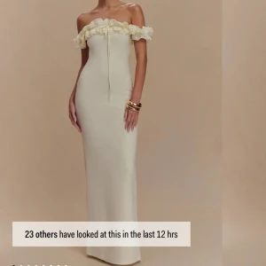 Ljus offshoulder långklänning med volang från meshki - Supersnygg slutsåld ljus långklänning från meshki med offshoulder och volangdetalj upptill. Klänningen har en figurnära passform och knytband framtill. Perfekt för bal eller student. Materialet känns slätt och elegant.
