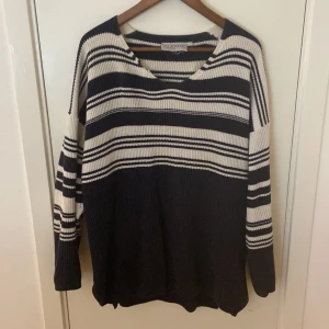 Randig stickad tröja från Classic - Säljer en stickad tröja från Classic i mörkblått och vitt med breda och smala ränder. Tröjan har v-ringad hals och långa ärmar, perfekt för dig som gillar chill och stilren look. Passar dig som vill ha en loose fit och mjukt material.