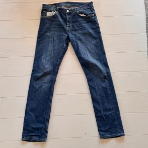 Blå jeans från J.Lindeberg straight fit - Snygga blå jeans från J.Lindeberg med klassisk femficksdesign och kontrastsömmar. Modellen har rak passform och normal midja, vilket ger en clean och tidlös look. Jeansen är tillverkade i mjukt denimtyg som sitter skönt hela dagen.