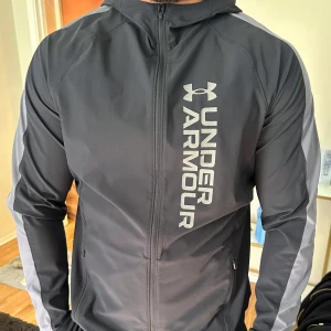 Vindjacka - Under Armor vindjacka i gråsvart färg, aldrig använd, storlek M.