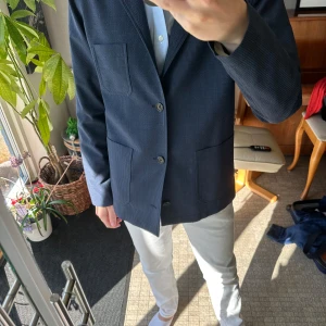 Blå kavaj från Matinique - Snygg mörkblå kavaj från Matinique i storlek EUR46. Kavajen har ett diskret  mönster, tre framfickor och klassisk knappstängning. Knapp använd i väldigt fint skick.