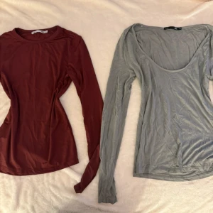 Vinröd och grå långärmad topp - Två stilrena långärmade toppar, en vinröd från lager 157 med rund hals och en grå från lager 157 med djupare urringning. Båda har en slim passform som sitter snyggt på kroppen. Perfekt att matcha med jeans eller kjol för en enkel look.