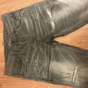 Gråa shorts från Dsquared2 - Snygga grå shorts från Dsquared2 med coola slitningar och blekta detaljer. Modellen har klassisk femficksdesign, knappgylf och Dsquared2-logga vid fickan. Jeansen är tillverkade i mjukt bomullstyg och har en modern, rak passform som ger en avslappnad vibe.