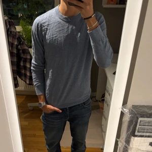 Ljusblå stickad tröja med rund hals - Snygg ljusblå stickad tröja med rund hals och långa ärmar. Tröjan har en enkel och clean design som passar perfekt till jeans. Mjuk och skön känsla, ribbade muddar vid ärmslut och nederkant. Perfekt för dig som gillar stilrena plagg.