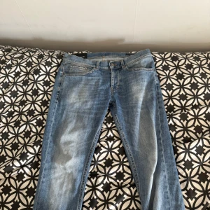 Dondup George skinny fit jeans blå - Snygga ljusblå jeans från Dondup, modell George med skinny fit. Klassisk femficksdesign, smal passform och slitningar framtill för en cool look. Tillverkade i mjukt jeanstyg med orangea sömmar och diskret logga på bakfickan. Perfekta för dig som gillar stilrena och moderna jeans. Pris går att diskutera!