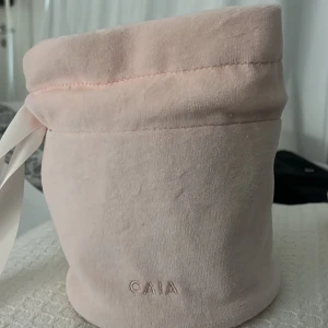 Ljusrosa sammetspåse från CAIA - Säljer en superfin ljusrosa sammetspåse från CAIA med rund form och vit satinband för snörning. Perfekt att använda som handväska eller förvaring av smink och småprylar. Mjuk och lyxig känsla, stilren design med diskret logga framtill. Även limeted edition 