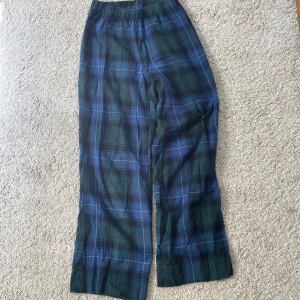 Flanell pyjamasbyxor - Säljer ett par rutiga flanellbyxor från H&M i storlek XS. De har en blå och grön färg. Byxorna är gjorda i 100% bomull, vilket gör dem sköna och mjuka.