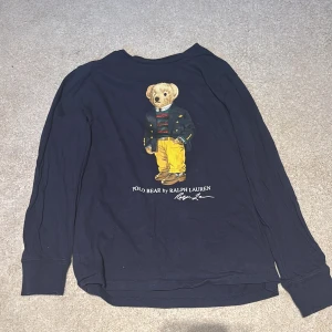 Mörkblå långärmad tröja Polo Bear - Säljer en mörkblå långärmad tröja från Ralph Lauren med ikoniskt Polo Bear-tryck på framsidan. Tröjan är ganska tunn så ingen tjock tröja. Vid snabb affär går priset att diskuteras