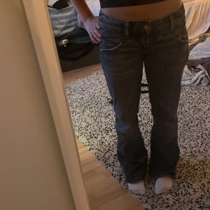 Blå bootcut jeans från Replay - Säljer ett par blå jeans från Replay med bootcut passform och låg midja. Jeansen har klassiska fem fickor, snygga slitningar och en Replay-logga på bakfickan. Materialet är robust denim som sitter skönt och ger en cool vibe.