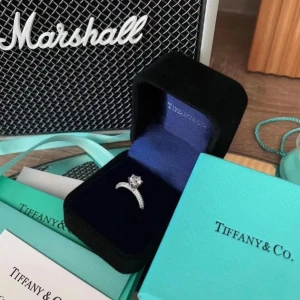 Tiffany & Co. silverring med diamant - Exklusiv silverring från Tiffany & Co. med en rundslipad diamant i klassisk fattning. Ringen har glittriga stenar längs bandet som ger extra lyxig känsla. Perfekt för dig som vill ha något tidlöst och elegant med ikonisk Tiffany-blå ask. Kommer i lådan o påsen