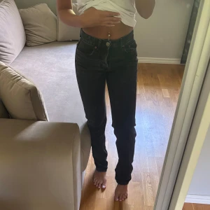 Svarta mid waist straight jeans - Säljer ett par svarta jeans med raka ben. Jeansen har klassisk femficksdesign och knappgylf. 