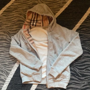 Grå Burberry hoodie med dragkedja - Säljer en grå hoodie för att den ej används. Den är helt ny och har inga skador. Hoodien är aldrig använd. Priset kan diskuteras vid snabb affär.