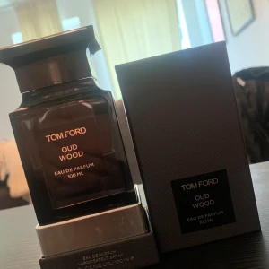 Tom Ford Oud Wood 50ml parfym - Exklusiv Tom Ford Oud Wood Eau de Parfum i 100 ml flaska. Flaskan är mörkbrun med elegant svart etikett och har en lyxig, fyrkantig design. Kommer med originalkartong i matchande mörk färg. En ikonisk doft med träiga och varma toner.