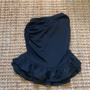 Svart volangkjol från Shein Teen - Supersöt svart kortkjol från Shein Teen med volangkant och snygg rynkning på sidorna. Kjolen har en elastisk midja och är gjord i mjukt syntetmaterial som sitter bekvämt. Perfekt för att skapa en trendig look med lite extra attityd.