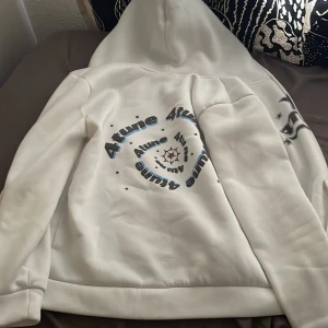 Vit hoodie med tryck från 4tune - Säljer en vit hoodie från 4tune med svart och blått tryck både fram och bak. Tröjan har huva, dragkedja och coola stjärndetaljer. Perfekt för dig som gillar streetwear och vill sticka ut med snygg grafik.