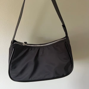 Svart liten axelväska  - En liten svart axelväska med många innerfack. 