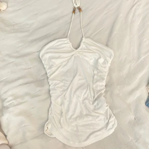 2000s summer top - Supersöt vit top från H&M Divided med halterneck och knytband dekorerade med pärlor. Toppen har rynkade sidor och ärmlös design, perfekt för varma dagar. 