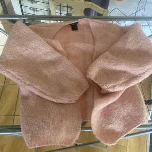 Ljusrosa stickad kofta från lindex - Supermysig ljusrosa stickad kofta från Vero Moda med oversized passform och långa ärmar. Perfekt att slänga över en topp för en chill och söt look. Koftan är öppen framtill och har en fluffig känsla som gör den extra cozy.