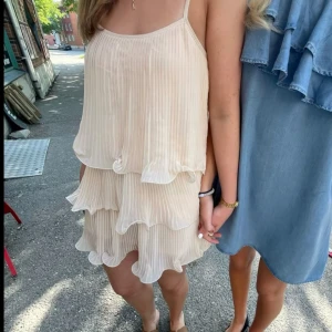 Champagnefärgad volangklänning H&M - Första och sista bilden är lånade. Superfin kort plisserad klänning från H&M i champagnefärg med tunna axelband och flera lager volanger. Lätt och flowy känsla, perfekt för sommarens varma dagar. Storlek M, passar dock även S.