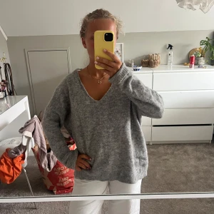 Grå stickad v-ringad tröja - Mysig grå stickad tröja med v-ringning och lång ärm. Tröjan har en loose passform och är perfekt för lager-på-lager. Den är enkel att matcha och har en mjuk känsla som gör den superbekväm.